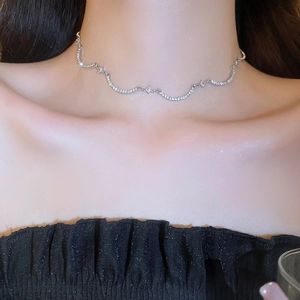 Primo piano della collana curva in argento e zirconi sul collo per un look elegante