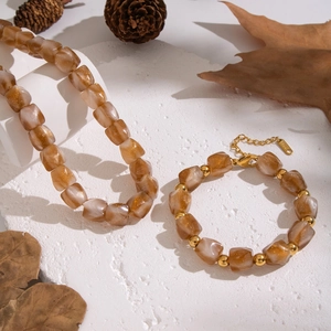 Brown gradient resin beaded jewelry set with flower charm on white textured stone