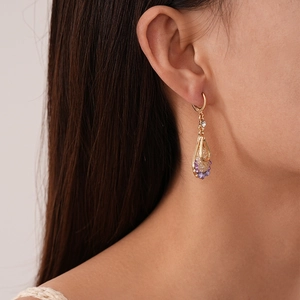 Detail of vintage teardrop earrings with purple crystal and pave zircon on model side view