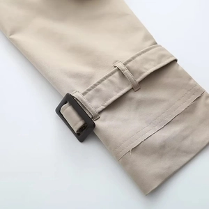 Gros plan du poignet d'un trench-coat kaki avec bride réglable et boucle en résine