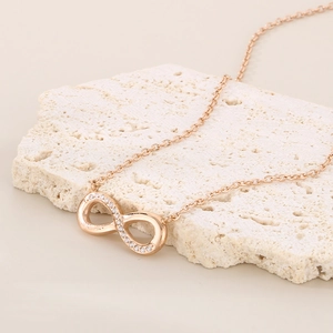 Macro shot of gold infinity pendant with tiny inset diamonds on textured stone base