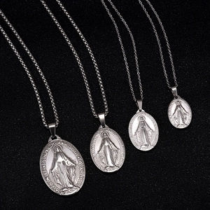 Detailed macro of four silver Virgin Mary oval pendants on textured dark background