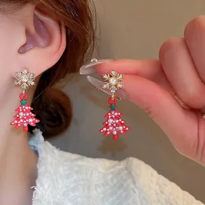 Orecchini di Natale con fiocco di neve e albero rosso, perle e cristalli sulla modella
