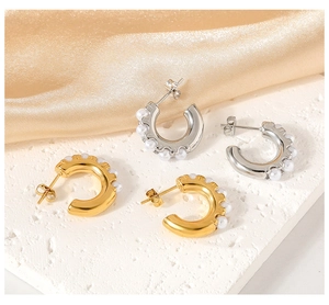 Detail of C-shaped stainless steel earrings with pearl inlay in gold and silver finish