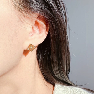 Close-up of golden snowflake stud earrings with sparkling zircon crystals on model