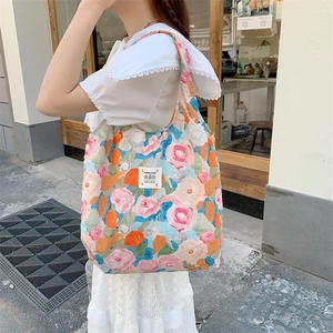 Dettaglio della trama a maglia della borsa floreale con patch LOVE su abito bianco