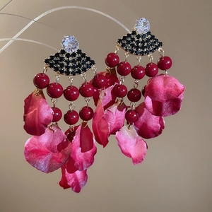 Detail of bohemian tassel earrings with fabric petals and metallic beadwork accents