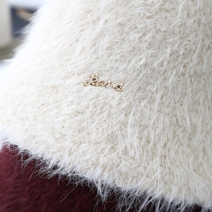 Chapeau cloche en fausse fourrure blanche avec logo métallique pour un look d'hiver chic
