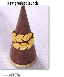 Detail of golden feather open ring showing intricate textures on wooden stand