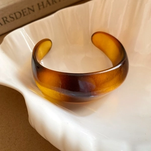 Detailed view of amber resin open bangle with translucent vintage texture on white ceramic