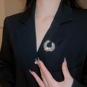 Close-up of a laurel wreath brooch with pearls and zircons on a black blazer jacket