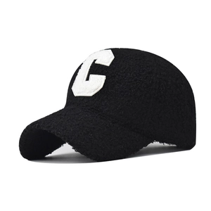 Close-up of white C-letter embroidery on black Sherpa fleece baseball cap texture
