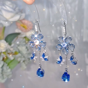 Detail of blue crystal flower earrings with teardrop tassels and silver metal plating