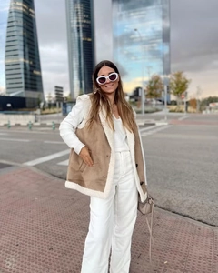 Outdoor shot of a women's camel suede vest with white faux fur lining and stand-up collar