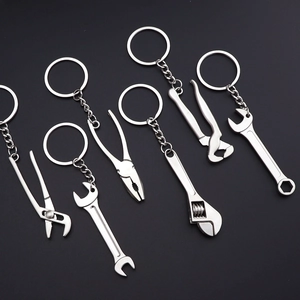 Miniature silver metal wrench and pliers tool keychain collection on a black background