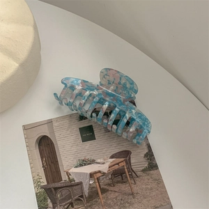 Detail of large acetate hair claw clip featuring blue and pink marble texture finish