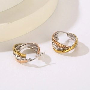 Macro shot of tricolor intertwined hoop earrings featuring gold, rose gold and silver bands