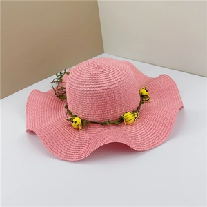 Détail d'un chapeau de soleil rose à bord ondulé et décorations d'abeilles jaunes