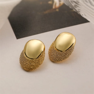 Close-up of golden geometric earrings featuring mixed smooth and matte metal textures
