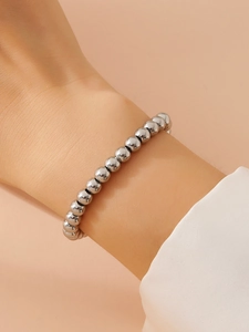Vista dettagliata del bracciale con perline d'argento al polso con finitura metallica