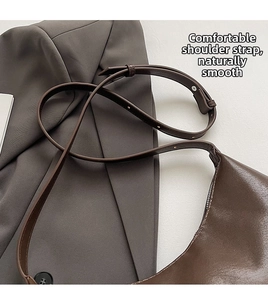 Detail of adjustable dark brown leather shoulder strap with fine metal hardware on bag