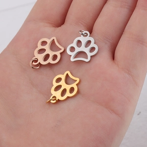 Trois pendentifs patte creuse en or rose, argent et or sur la paume pour voir la taille