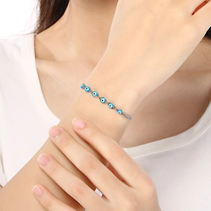 Detail of adjustable evil eye resin bead bracelet with stainless steel heart charm on wrist