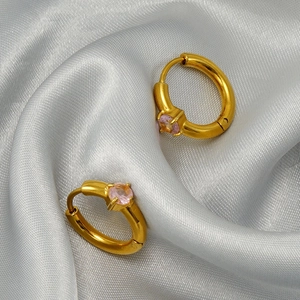 Minimalist gold hoop earrings with light pink zircon inlay on a white silk surface