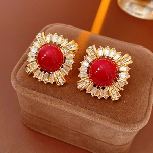 Macro shot of vintage gold earrings with red round stone and shimmering rhinestones