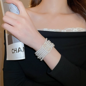 Detail of multi-strand pearl bracelet with crystal-studded hollow square clasp on wrist