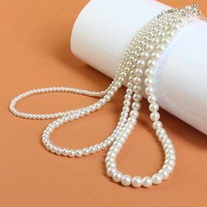 Close-up of French style pearl necklace with metallic clasp on a warm orange backdrop