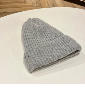 Dettaglio del berretto in maglia grigio chiaro con trama di lana spessa e bordo risvoltato