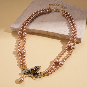 Detalle de collar de perlas champán de doble capa con un colgante de mariposa de cristal brillante