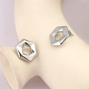 Detailed view of silver hexagonal geometric stud earrings on a ceramic display