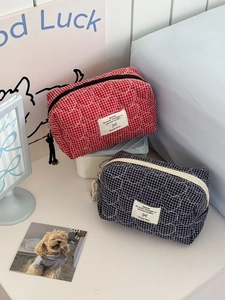 Détail de trousses de maquillage matelassées cœur en rouge et bleu marine à fermeture