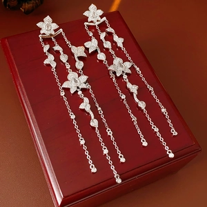 Macro detail of silver tassel flower earrings with cubic zirconia on a red wood jewelry box