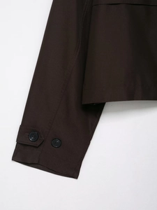 Close-up of cuff buttons and fine stitching on dark brown double-breasted trench coat