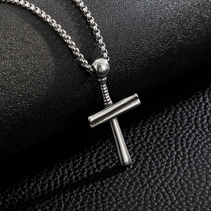 Macro shot of silver baseball cross pendant in titanium steel on dark leather texture
