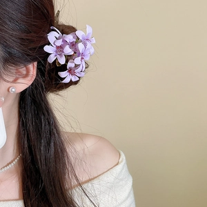 Detailed view of elegant purple fabric flower hair pin worn on long dark hair