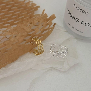 Detail of interlocking wavy silver and gold layered rings on a minimalist background