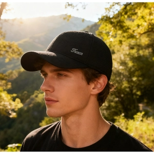 Profile view of black baseball cap with Jeans embroidery against a sunset mountain backdrop
