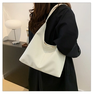 Grande borsa a tracolla beige in pelle morbida indossata con un cappotto nero invernale