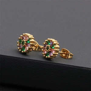 Macro detail of gold flower earrings with emerald green and lavender zircon stones