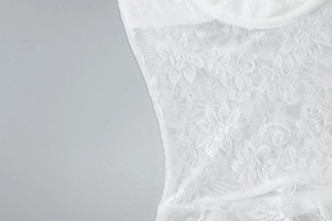 Macro view of white floral lace fabric showing delicate mesh texture and embroidery detail