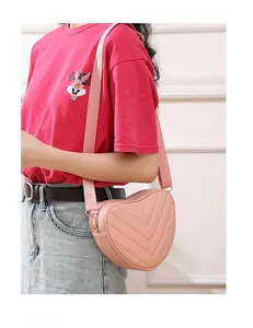 Detailed view of heart-shaped crossbody bag with V-quilted faux leather and woven strap