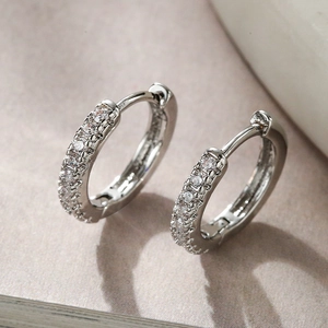 Elegant silver-plated hoop earrings with sparkling cubic zirconia on a textured background