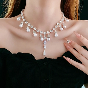 Detailed view of elegant necklace with water-drop zircons and white pearls on model