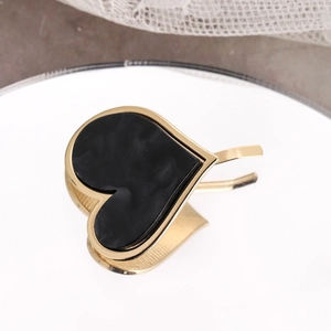 Detail of a black heart-shaped hair clip with gold metal trim on a lace background