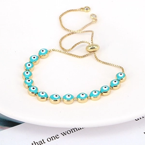 Detail view of gold chain bracelet featuring blue evil eye charms and adjustable slider