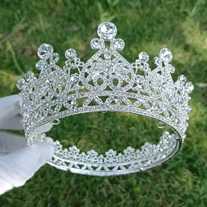 Elegant bridal silver crown with sparkling rhinestones held against a natural green background